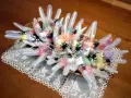 Manualidades chuches Halloween: guantes transparentes rellenos de caramelos y decorados con arañas negras, presentados en una cesta sobre un mantel de encaje.