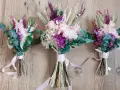 Tres ramos de flores secas y eucalipto, atados con cintas rosas. Un detalle que regala la madrina de boda a los novios.