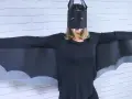 Persona con un disfraz murciélago casero, alas negras y máscara con colmillos.