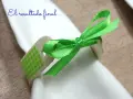 Servilleteros caseros originales: un detalle de madera con cinta verde brillante y patrón de cuadros, atado a una servilleta blanca.