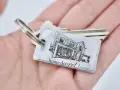 Un llavero hogar con la imagen de una casa y la frase "home sweet home" descansa en una mano.