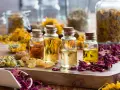 Botellas con aceites esenciales y pétalos de rosa, manzanilla y caléndula. Ideas para saber como hacer esencias aromaticas caseras.