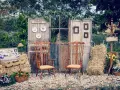 Un rústico photocall boda casero con puertas antiguas, sillas de madera, balas de heno y detalles florales.