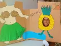 Divertido photocall hawaiano casero con una figura de bailarina y una piña con cara sonriente. ¡Perfecto para unas fotos tropicales!