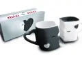 Dos tazas de amor, una negra y otra blanca, con forma de rostros que se miran. La caja dice "mia & mio".