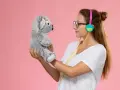 Mujer con auriculares sostiene un peluche de koala gris, como si compartieran secretos. ¡Un par de osos personalizados para la diversión!
