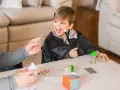 Niño con túnica de mago practica trucos de magia para niños con las manos, usando varita y cartas.