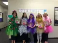 Cinco mujeres con disfraces caseros inspirados en "Ricitos de Oro" y los osos, cada una representando un color: verde, plateado, morado, dorado y rosa.