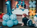 Niño gateando junto a globos azules y un gran número 1. Ideas para como preparar una fiesta infantil barata y muy original.