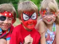 Niños con pintacaras de pirata, Spider-Man y mariposa sonriendo.