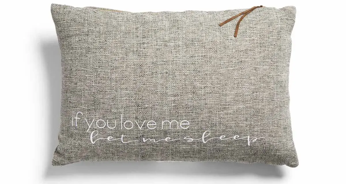 Cojines con frases: uno gris con "if you love me let me sleep" bordado en blanco y un detalle de cuero.