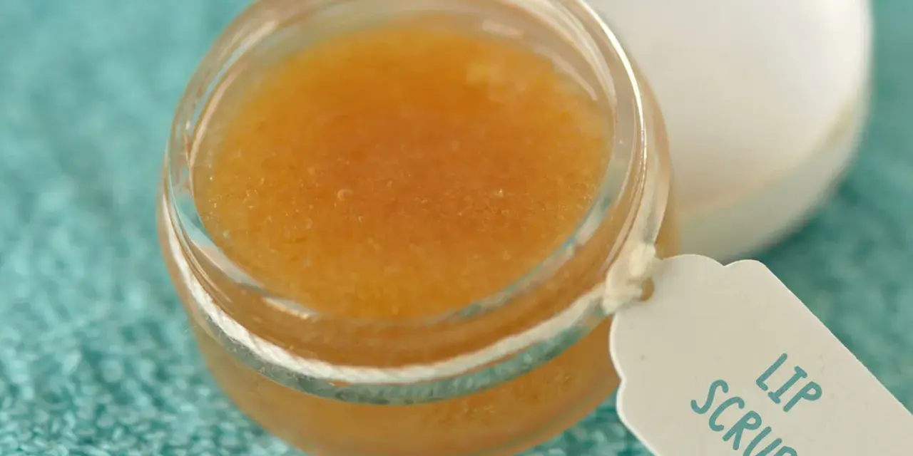 Un tarro de exfoliante de labios casero con etiqueta "Lip Scrub" sobre una toalla turquesa.