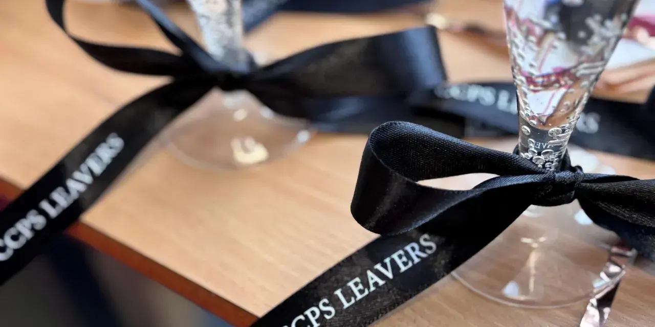 Copas de champán con lazos personalizados negros con el texto "CCPS LEAVERS" para una celebración especial.