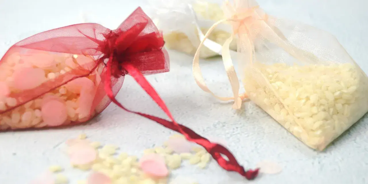 Bolsitas de organza rojas, blancas y melocotón llenas de arroz, listas para usarse como recuerdo. Ideas para como hacer bolsitas de arroz para bodas.