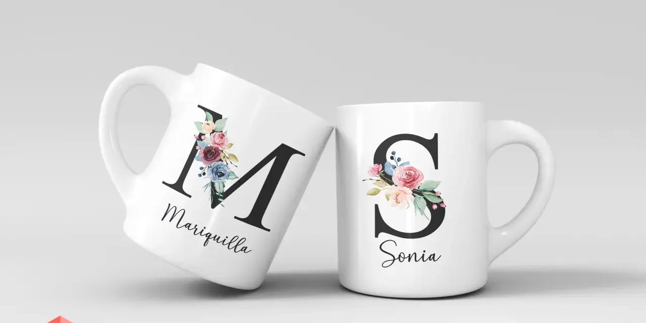 Dos tazas blancas con iniciales decoradas con flores. Una tiene la "M" de Mariquilla, la otra la "S" de Sonia.