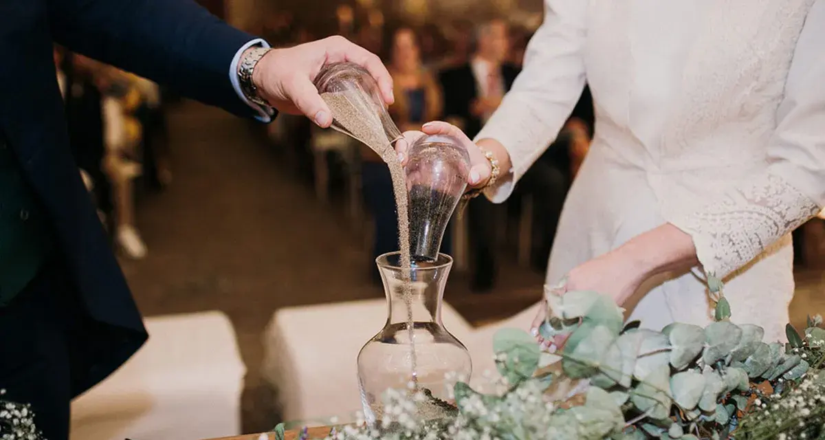 Manos unidas en el ritual de la arena boda, mezclando sus vidas en un solo recipiente.