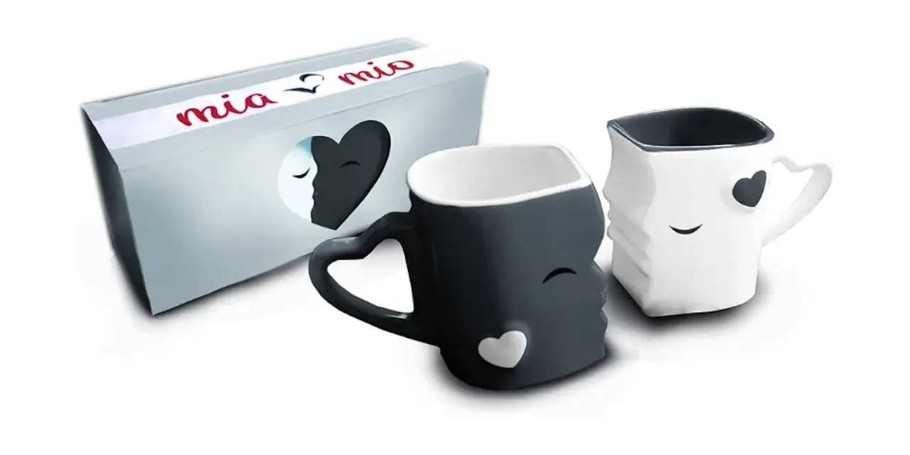 Dos tazas de amor, una negra y otra blanca, con forma de rostros que se miran. La caja dice "mia & mio".