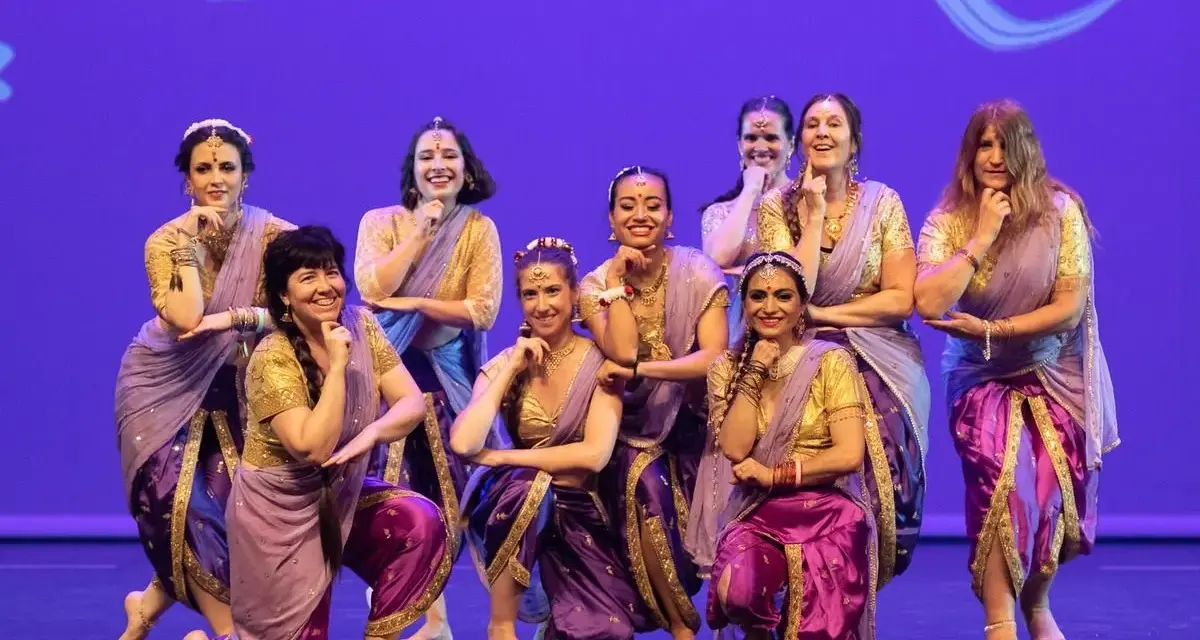 Un grupo de mujeres sonríe y posa con trajes vibrantes, listas para una fiesta bollywood.
