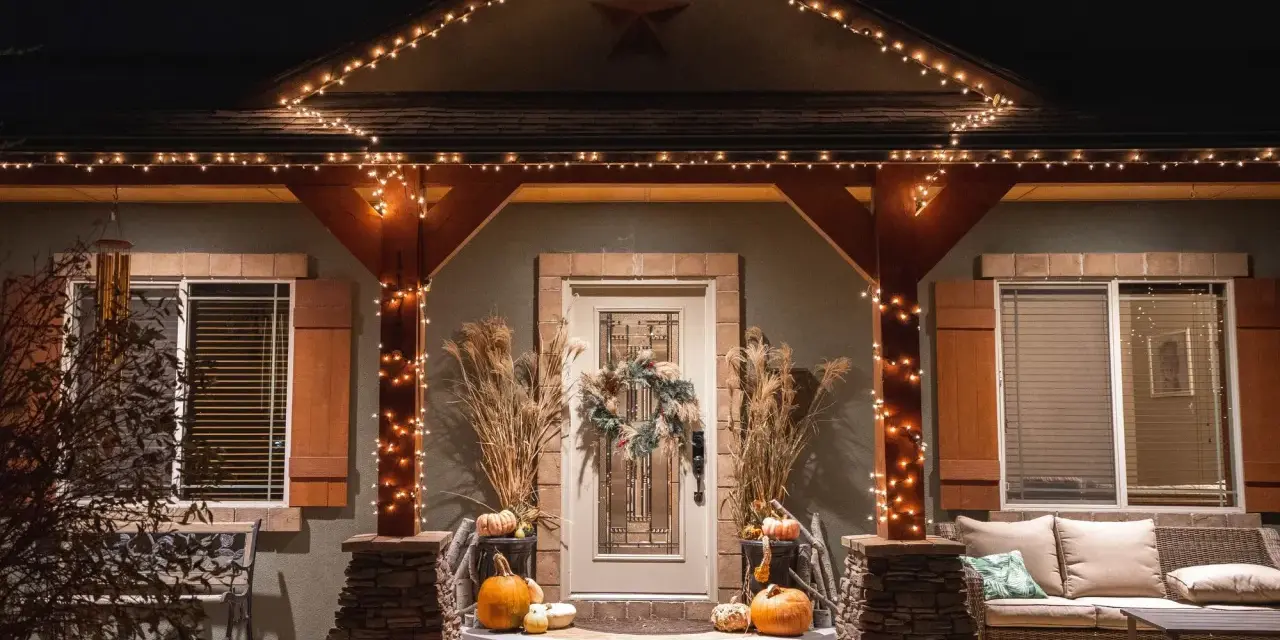 Encantadora decoración Halloween exterior casera con calabazas, luces cálidas y un porche acogedor.