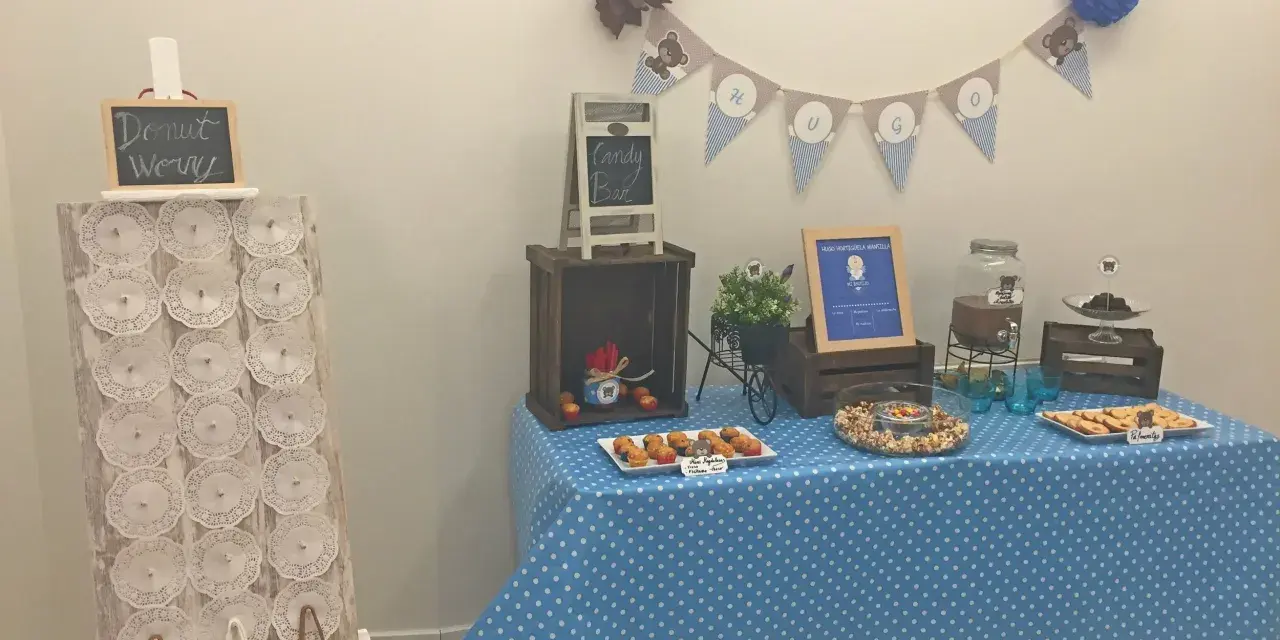 Mesa de dulces con temática de ositos, incluyendo un candy bar casero con magdalenas, galletas y palomitas.