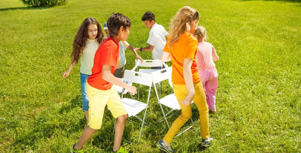 Niños jugando a las sillas musicales, uno de los 20 juegos para fiestas infantiles.