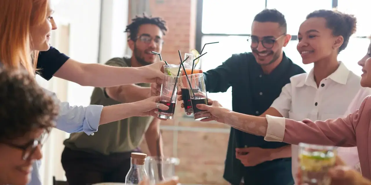 Grupo de amigos brindando con bebidas, inspirando temáticas para juegos de mesa y celebraciones.