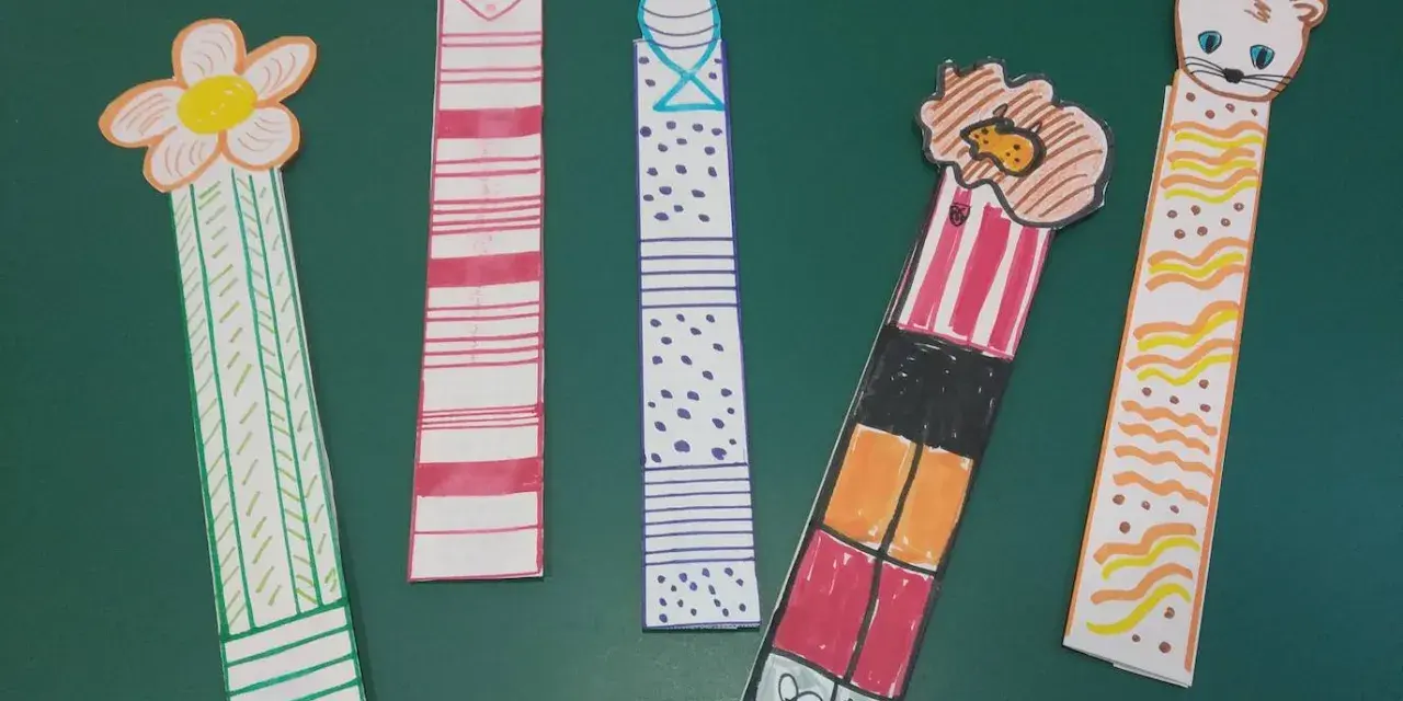 Cinco marcapáginas caseros: uno con flor, otro con corazón, uno con puntos, uno con un personaje y otro con un gatito.