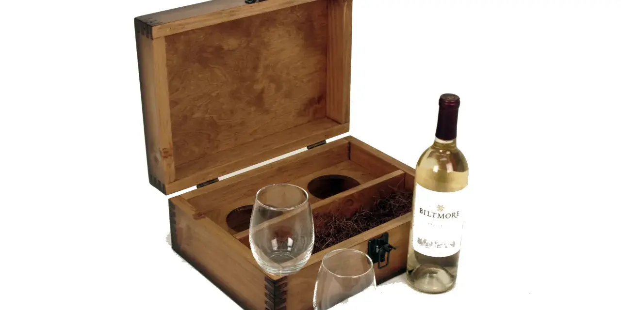 Caja de madera abierta con dos copas, paja decorativa y una botella de vino blanco. Un set vino personalizado perfecto para regalar.