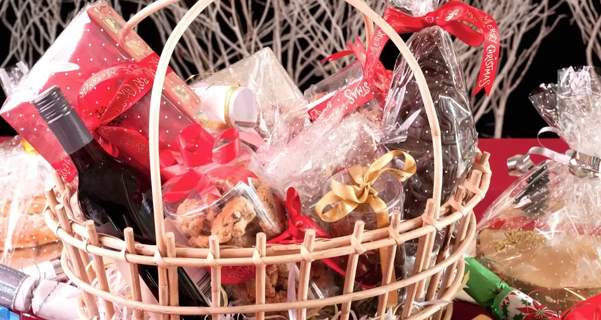 Canasta llena de dulces, galletas, una botella de vino y adornos navideños. ¡Perfecta para ideas para rifar!