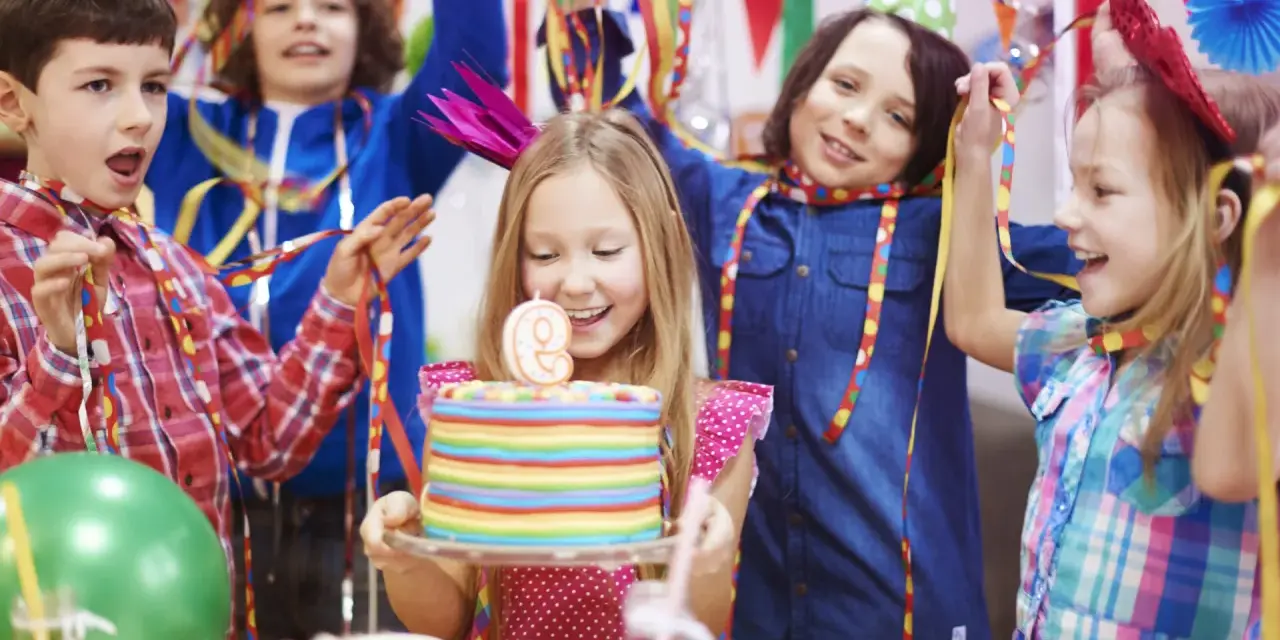 Niños celebran una temática fiesta infantil con pastel de cumpleaños, globos y serpentinas. ¡Alegría y diversión garantizadas!