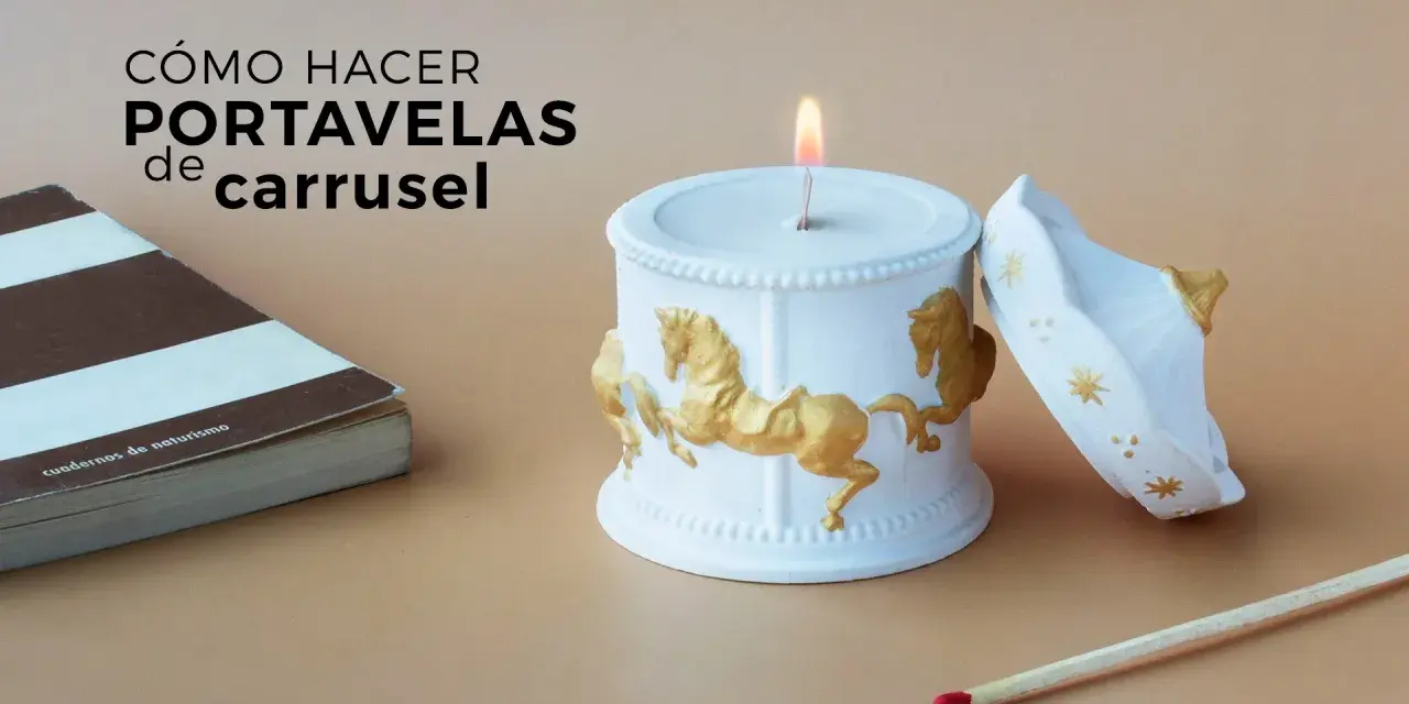 Portavelas manualidades de carrusel, blanco con caballos dorados, junto a un libro y una cerilla.