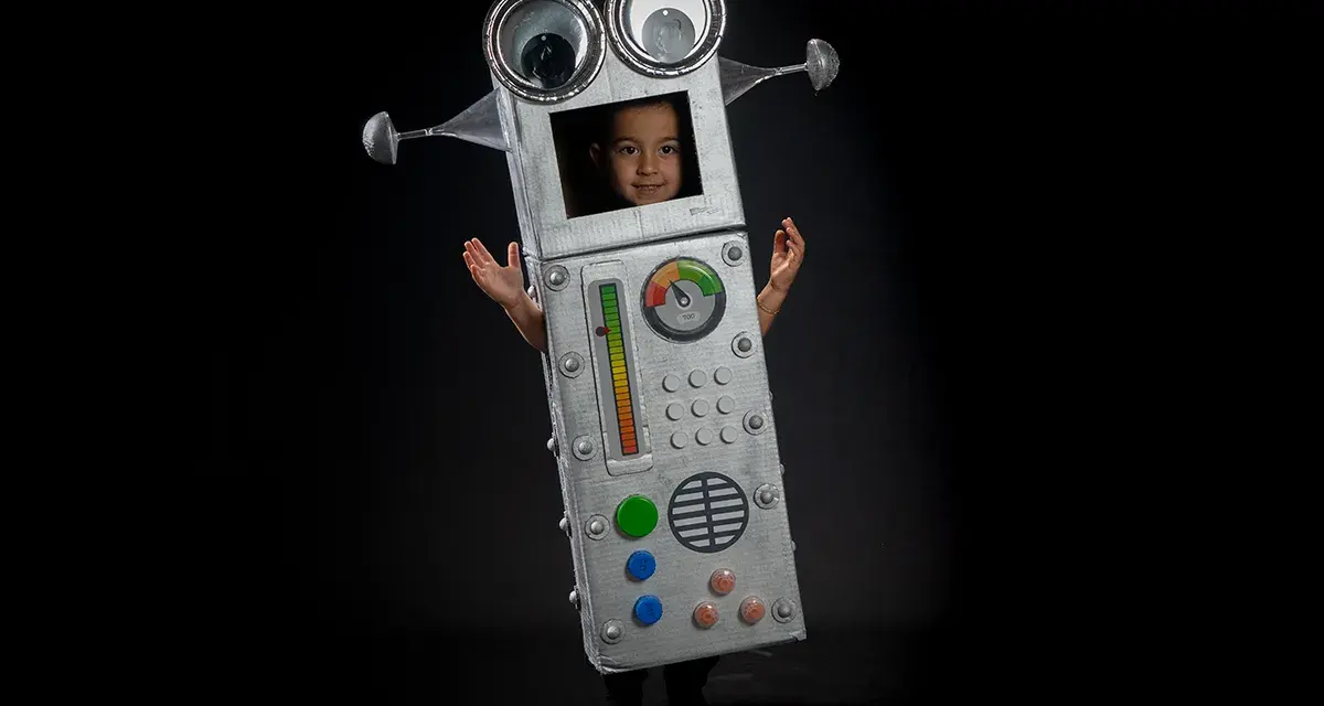 Niño con un divertido disfraz robot casero, con ojos saltones y panel de control. ¡Listo para la aventura!