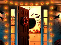 Guirnalda de calabazas iluminadas y murciélagos de cartón crean una espeluznante decoración de terror casera frente a una puerta.