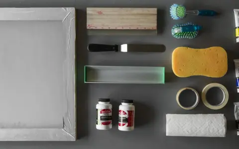 Marco de serigrafía, rasquetas, esponja, cintas, papel, cepillos y tubos de pintura acrílica, todo listo para empezar con los materiales serigrafia.