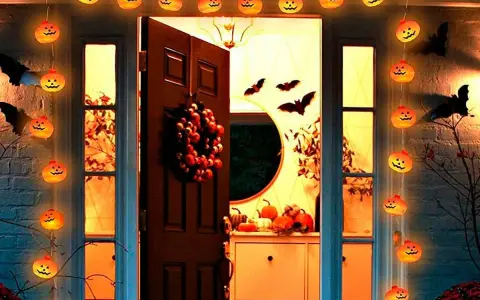 Guirnalda de calabazas iluminadas y murciélagos de cartón crean una espeluznante decoración de terror casera frente a una puerta.