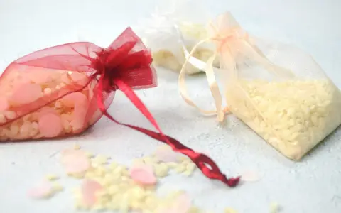 Bolsitas de organza rojas, blancas y melocotón llenas de arroz, listas para usarse como recuerdo. Ideas para como hacer bolsitas de arroz para bodas.