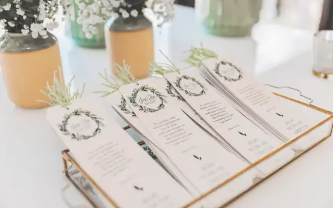 Detalle de invitaciones de boda caseras con diseño floral y versículos bíblicos, listas para entregar.