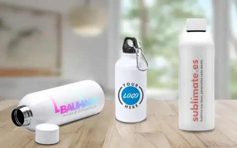 Tres bidones personalizados en una mesa de madera. Uno con logo "BAUHAUS", otro con "YOUR LOGO HERE" y el tercero con "sublimate.es".