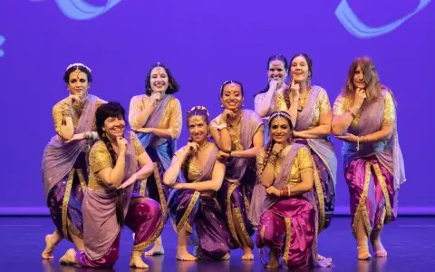 Un grupo de mujeres sonríe y posa con trajes vibrantes, listas para una fiesta bollywood.