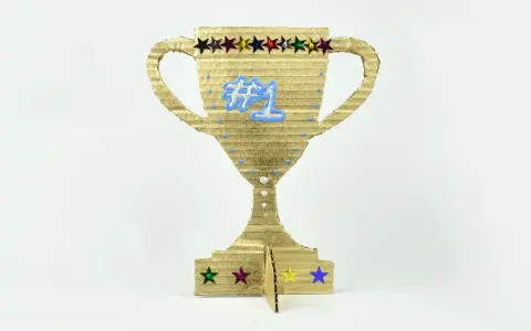 Trofeo de cartón dorado, ideal para hacer trofeos personalizados. Luce un "#1" azul y estrellas de colores.