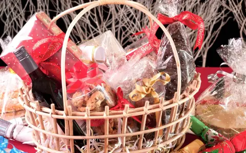Canasta llena de dulces, galletas, una botella de vino y adornos navideños. ¡Perfecta para ideas para rifar!