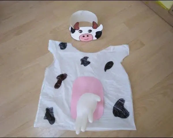 Originales disfraces con bolsas de basura: un traje de vaca blanco con manchas negras y una ubre rosa, junto con una diadema de vaca.