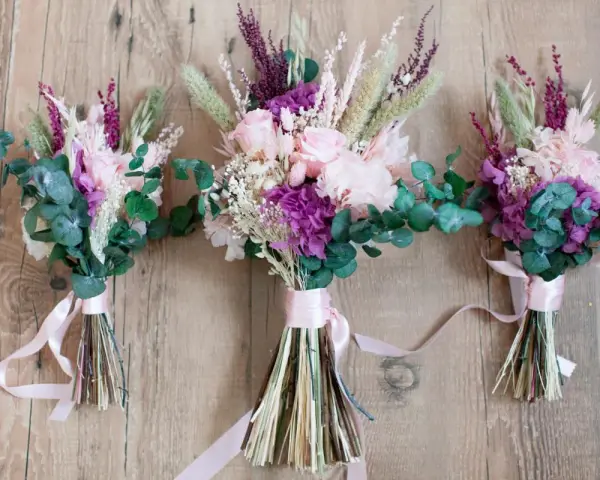 Tres ramos de flores secas y eucalipto, atados con cintas rosas. Un detalle que regala la madrina de boda a los novios.
