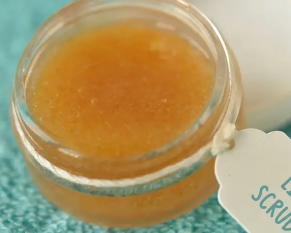 Un tarro de exfoliante de labios casero con etiqueta "Lip Scrub" sobre una toalla turquesa.