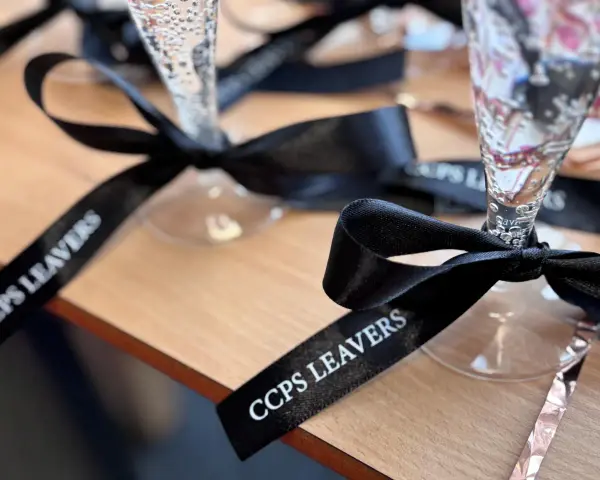 Copas de champán con lazos personalizados negros con el texto "CCPS LEAVERS" para una celebración especial.