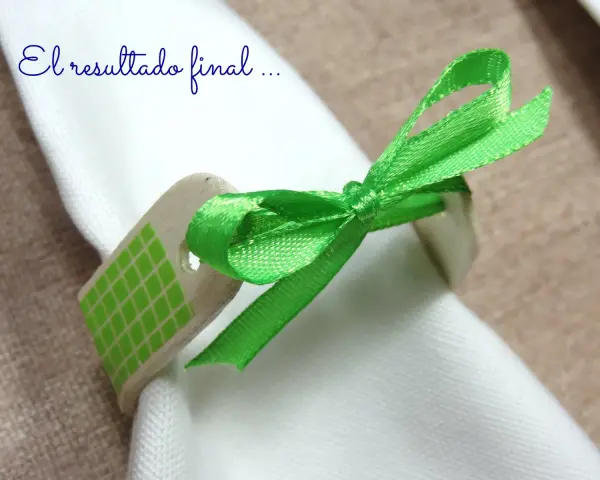Servilleteros caseros originales: un detalle de madera con cinta verde brillante y patrón de cuadros, atado a una servilleta blanca.