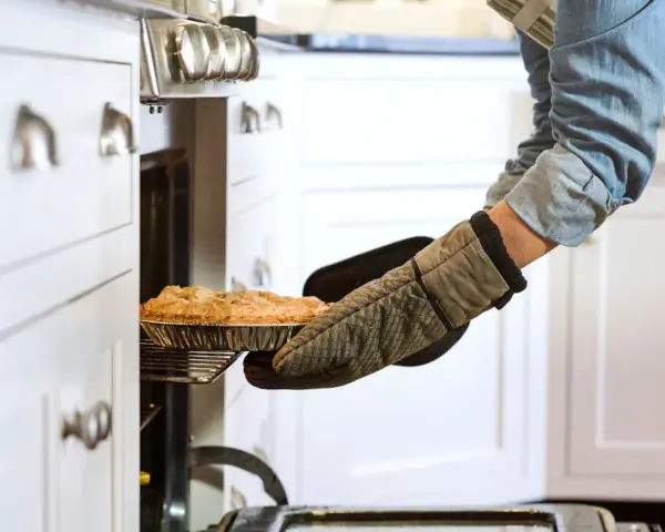 Persona saca un pastel del horno con guantes de cocina personalizados.