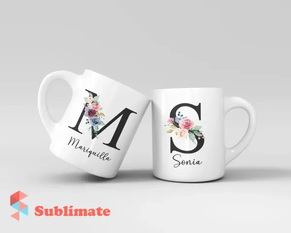 Dos tazas blancas con iniciales decoradas con flores. Una tiene la "M" de Mariquilla, la otra la "S" de Sonia.