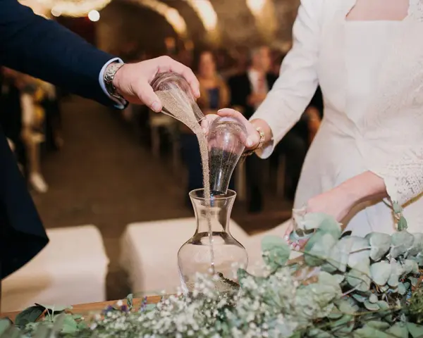 Manos unidas en el ritual de la arena boda, mezclando sus vidas en un solo recipiente.