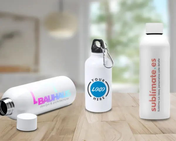 Tres bidones personalizados en una mesa de madera. Uno con logo "BAUHAUS", otro con "YOUR LOGO HERE" y el tercero con "sublimate.es".
